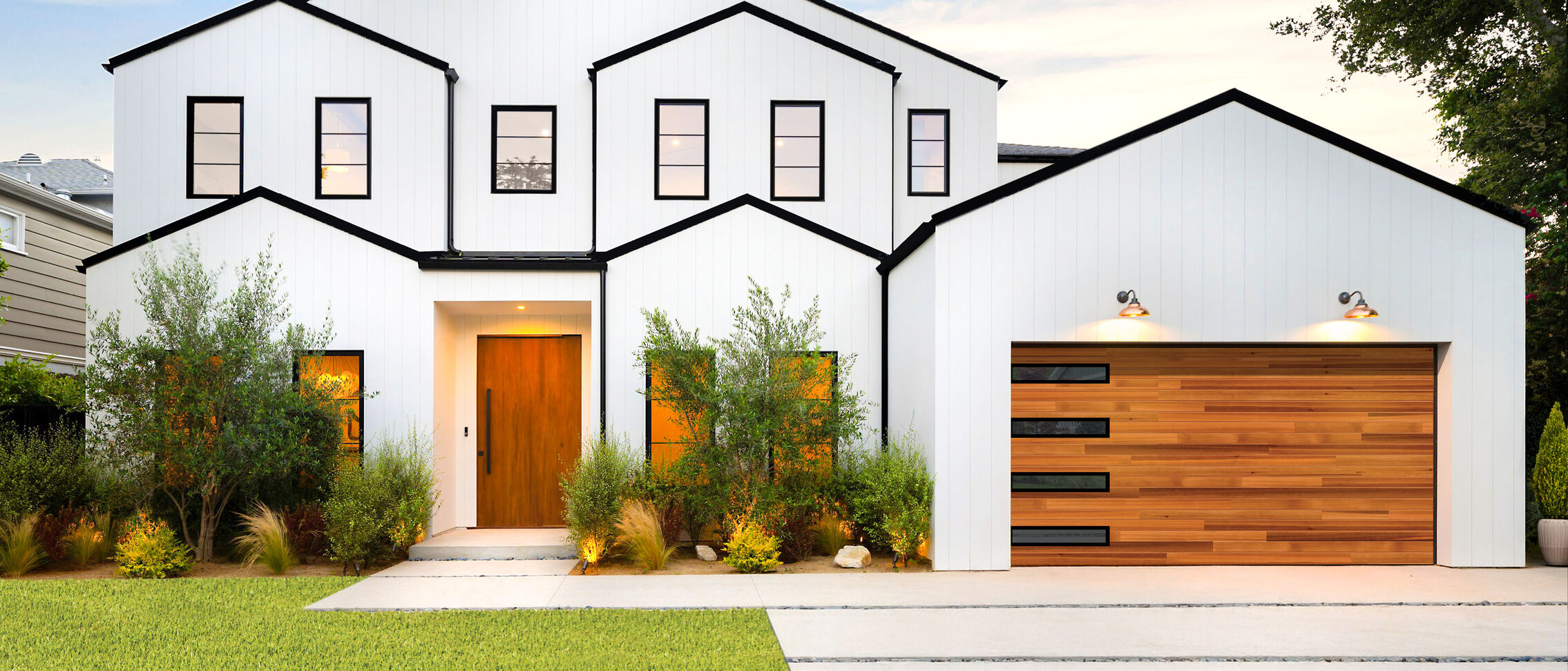 Modern white house with wooden accents at dusk.